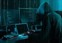 Hacker in dark room surrounded by computer screens