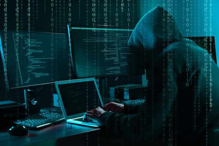 Hacker in dark room surrounded by computer screens