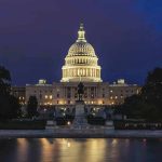 Illuminated capitol building at night with reflection in water