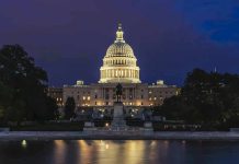 Illuminated capitol building at night with reflection in water