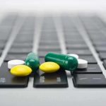 Various colored pills scattered on a laptop keyboard