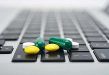 Various colored pills scattered on a laptop keyboard