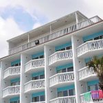 Exterior view of a beachfront hotel with balconies and colorful towels hanging