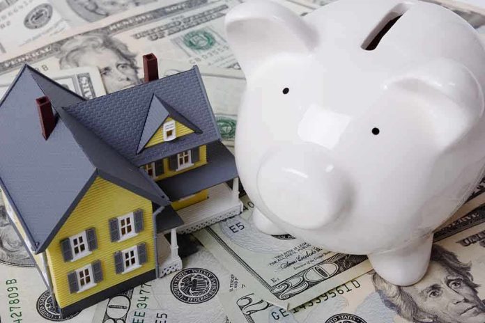 shutterstock_2018367.jpg A model house next to a white piggy bank on a bed of dollar bills