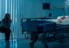 Woman sitting beside hospital bed at night