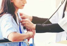 Doctor examining patient with stethoscope in hospital