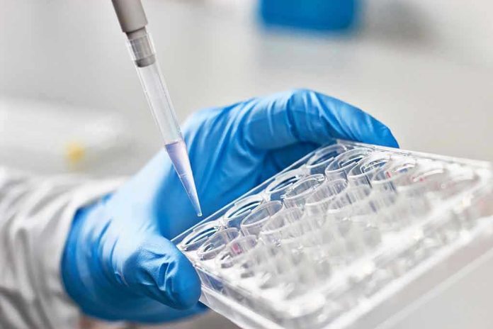 612999197 Gloved hand pipetting liquid into a tray