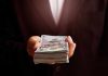 Hand holding a stack of hundred dollar bills