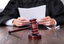 A judge holding documents with a gavel in the foreground