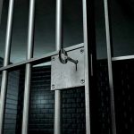 Close-up of a locked prison gate with metal bars
