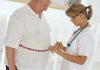A healthcare professional measuring a patients waist with a tape measure