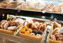 A display case filled with various types of baked goods including breads and pastries