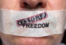 Close up of a persons mouth covered with tape that reads CENSORED FREEDOM