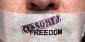 Close up of a persons mouth covered with tape that reads CENSORED FREEDOM