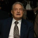 Elderly man in a suit sitting at a dining table during a formal event