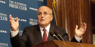 A man in a suit speaking at a podium during a press conference
