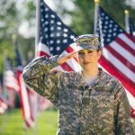 Soldier saluting in front of American flags outdoors