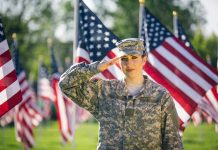Soldier saluting in front of American flags outdoors