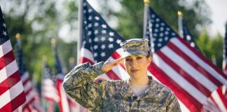 Soldier saluting in front of American flags outdoors