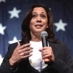 Woman speaking with microphone American flag background